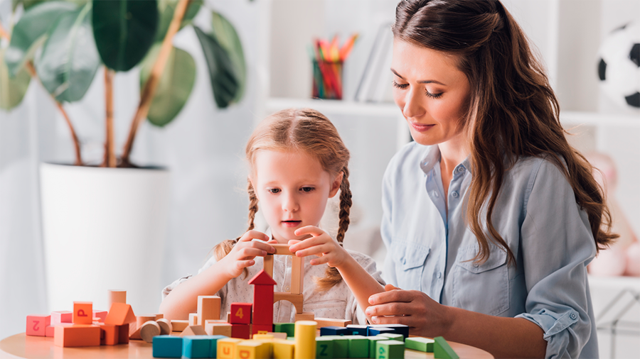 Mulher acompanha a criança brincando com os blocos de montar